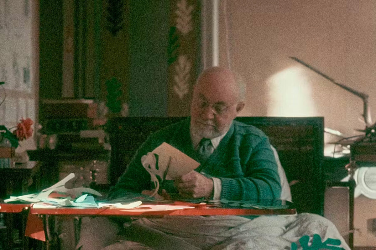 Henri Matisse late in life, cutting shapes out of painted paper at his table